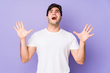 Young man isolated on purple background screaming to the sky, looking up, frustrated.