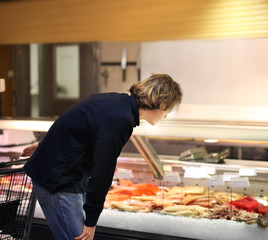 man shopping for fresh fish seafood in supermarket retail store	