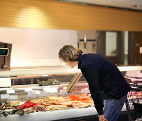 man shopping for fresh fish seafood in supermarket retail store	