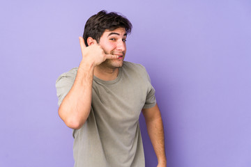 Young man isolated on purple background showing a mobile phone call gesture with fingers.