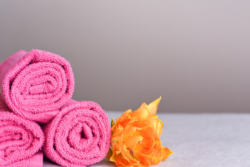 Obraz na płótnie Canvas a stack of new clean pink towels in rolls with a yellow flower, the concept of freshness and cleanliness