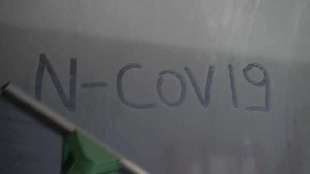 Pandemic and emergency Coronavirus n-cov19, written on wet glass and window cleaner that eliminates the writing - defeat the virus born in China and widespread in Europe, Africa and America