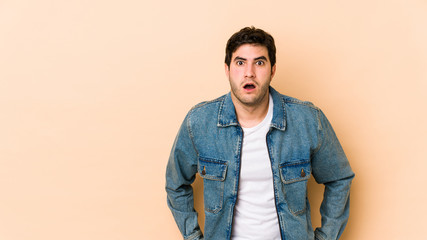 Young man isolated on beige background being shocked because of something she has seen.