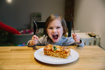 Little girl with a lasagne bolognese in a cafe