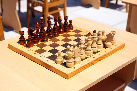 Yellow and brown photo with a picture of a chess Board pieces, Wooden pieces on a chess Board and emtye table . How to play wooden chess game. Chess board with yellow and brown figures .