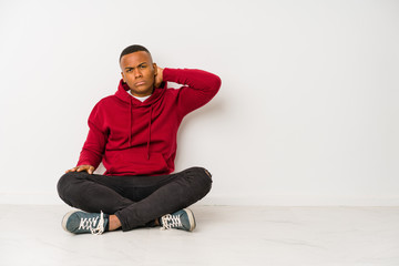 Young latin man sitting on the floor isolated suffering neck pain due to sedentary lifestyle.