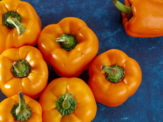 Classic blue background color.Fresh orange sweet peppers lie against a classic blue background