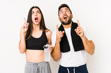 Young caucasian fitness couple isolated pointing upside with opened mouth.