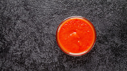 Mexican cuisine. Salsa tomato sauce in a transparent gravy boat on a black background. background image, copy space text