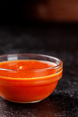 Mexican cuisine. Salsa tomato sauce in a transparent gravy boat on a black background. background image, copy space text