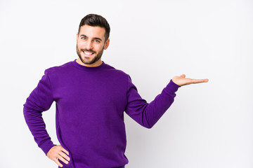 Young caucasian man against a white background isolated showing a copy space on a palm and holding another hand on waist.