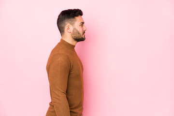Young caucasian man against a pink background isolated gazing left, sideways pose.