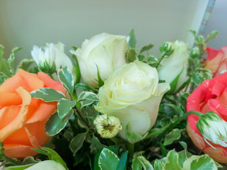 A bright bouquet of different colors roses, decorated with green twigs.