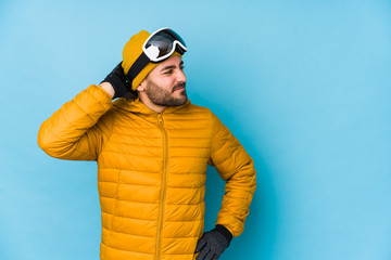 Young skier caucasian man isolated touching back of head, thinking and making a choice.