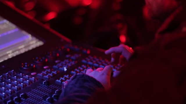 Audio mix desk at a concert. Man working on professional digital audio channel mixer in studio. Male Dj hands playing set in night club party slow motion