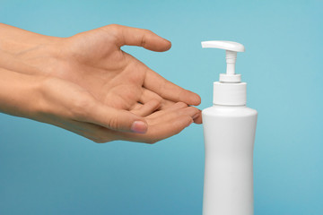 Woman washes her hands using liquid soap on a blue background. Girl uses liquid disinfectant to protect against COVID-19. Recommendation of World Health organisation for hands washing