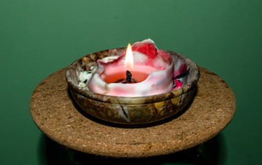 A close up photo of a single light candle melts in a small pot. 