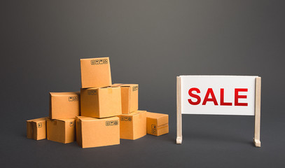 Cardboard boxes with goods and a sale stand. Big sale discounts on favorable terms. Shopping event....
