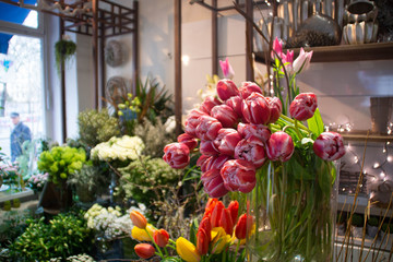 Fototapeta na wymiar Bouquet of tulips and some plants on the background in a flower shop