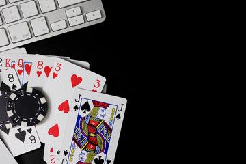 Poker cards and black chips with computer keyboard reference isolated on a black background.Concept of betting and online play.Copy space.