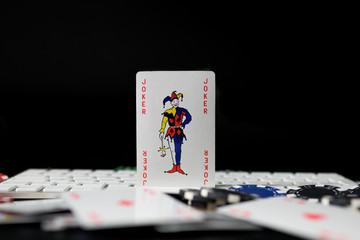 Poker card on computer keyboard with chips and poker cards unfocused in first term. Concept of betting and online game, with copy space