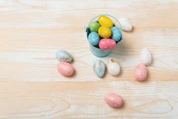 Colorful Easter eggs in bucket on wooden background. Festive eggs. Top view