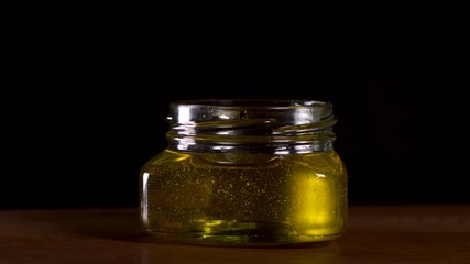 Honey dripping from honey dipper on black background. Healthy organic Thick honey dipping from the wooden honey spoon..