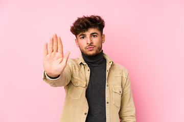 Young arabian man posing in a background isolated standing with outstretched hand showing stop sign, preventing you.