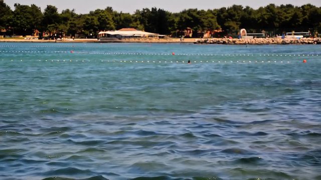 Landscape view to the sea bay with beaches and people bathing in the sea during hot summer day in Umag, Croatia.