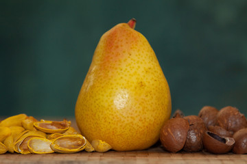 Ripe pear among shells from pistachios and macadamia