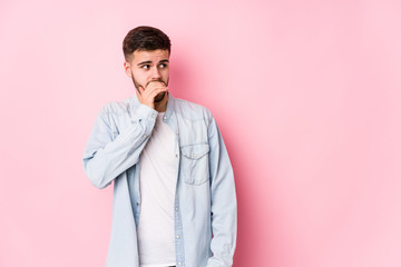 Young caucasian business man posing in a white background isolated thoughtful looking to a copy space covering mouth with hand.< mixto >