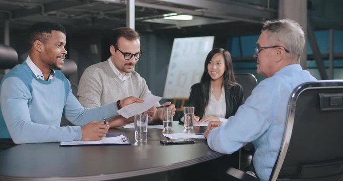 Mature bank agent shaking hands with client after signing agreement