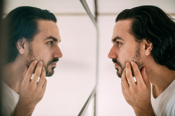 A handsome man looks in the mirror. Men's personal care