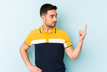 Young caucasian man isolated on blue background pointing with finger at you as if inviting come closer.
