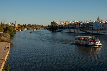 Naklejka premium Crucero fluvial por el río Guadalquivir en Sevilla, al fondo la torre del oro y el barrio de Triana