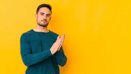 Young caucasian man isolated on yellow bakground feeling energetic and comfortable, rubbing hands confident.