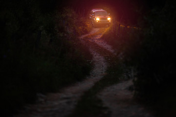 Car driving at night on winding narrow rural road