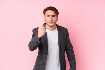 Young caucasian business man posing isolated showing fist to camera, aggressive facial expression.