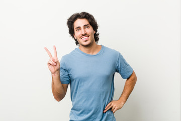 Fototapeta premium Young handsome man against a white background joyful and carefree showing a peace symbol with fingers.