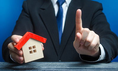 Man with a house makes a gesture of attention. Legal advice on terms a contract deal for purchase...