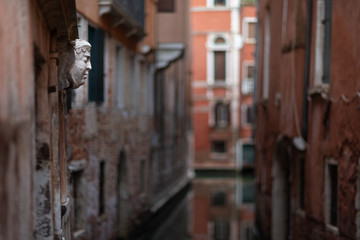 Fototapeta na wymiar A wall sculpture seen from the bridge over the rio della Veste along Calle del Caffettier. Background in soft focus.