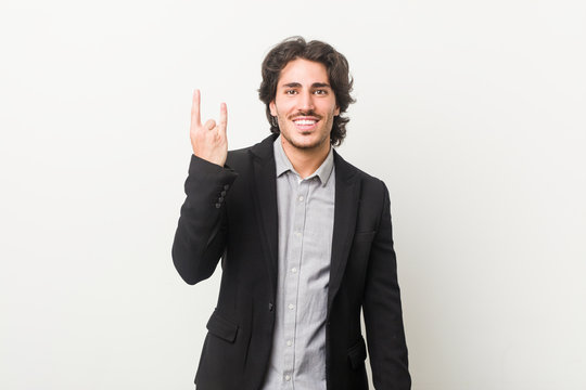 Young business man against a white background showing a horns gesture as a revolution concept.