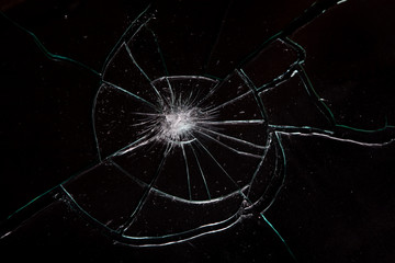 Broken glass with spider web cracks on black background