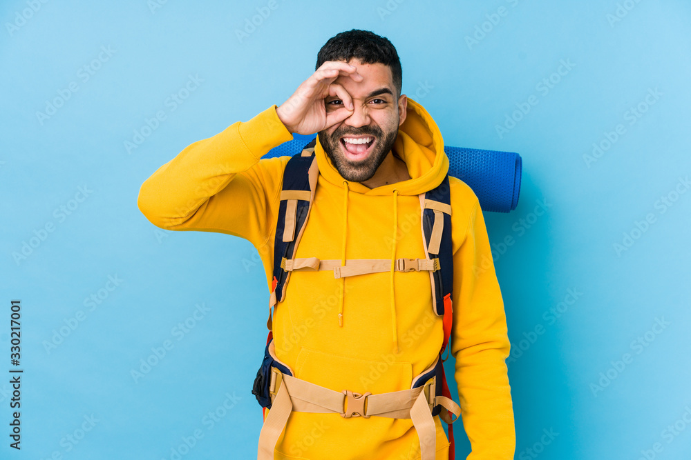 Wall mural young arabian traveler backpacker man isolated excited keeping ok gesture on eye.