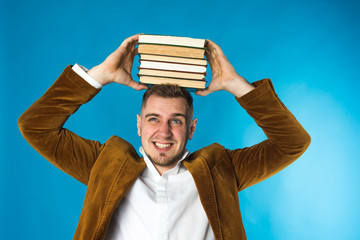 young stylish European business man, businessman, student in suit holding books on his head, on...