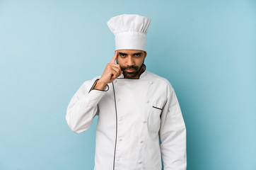 Young latin chef man isolated pointing temple with finger, thinking, focused on a task.