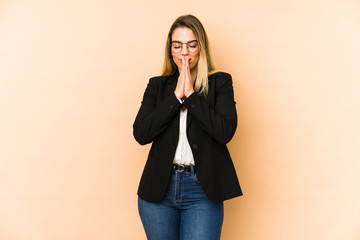 Middle age business woman isolated on beige background holding hands in pray near mouth, feels confident.