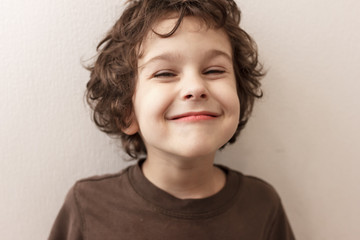 very pleased curly-haired boy with closed eyes in pleasure on white background