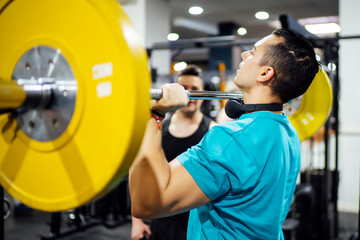 Two men training in gym lifting weights.