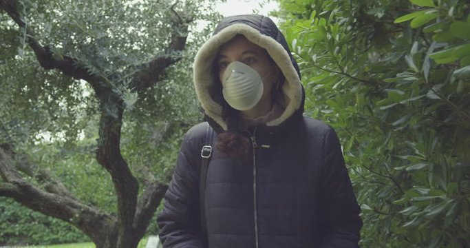 young woman wears a mask to protect herself from covid-19 while walking in nature. shot in slow motion